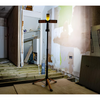 Lamp on a stand in a room under renovation with exposed walls and wooden floor.