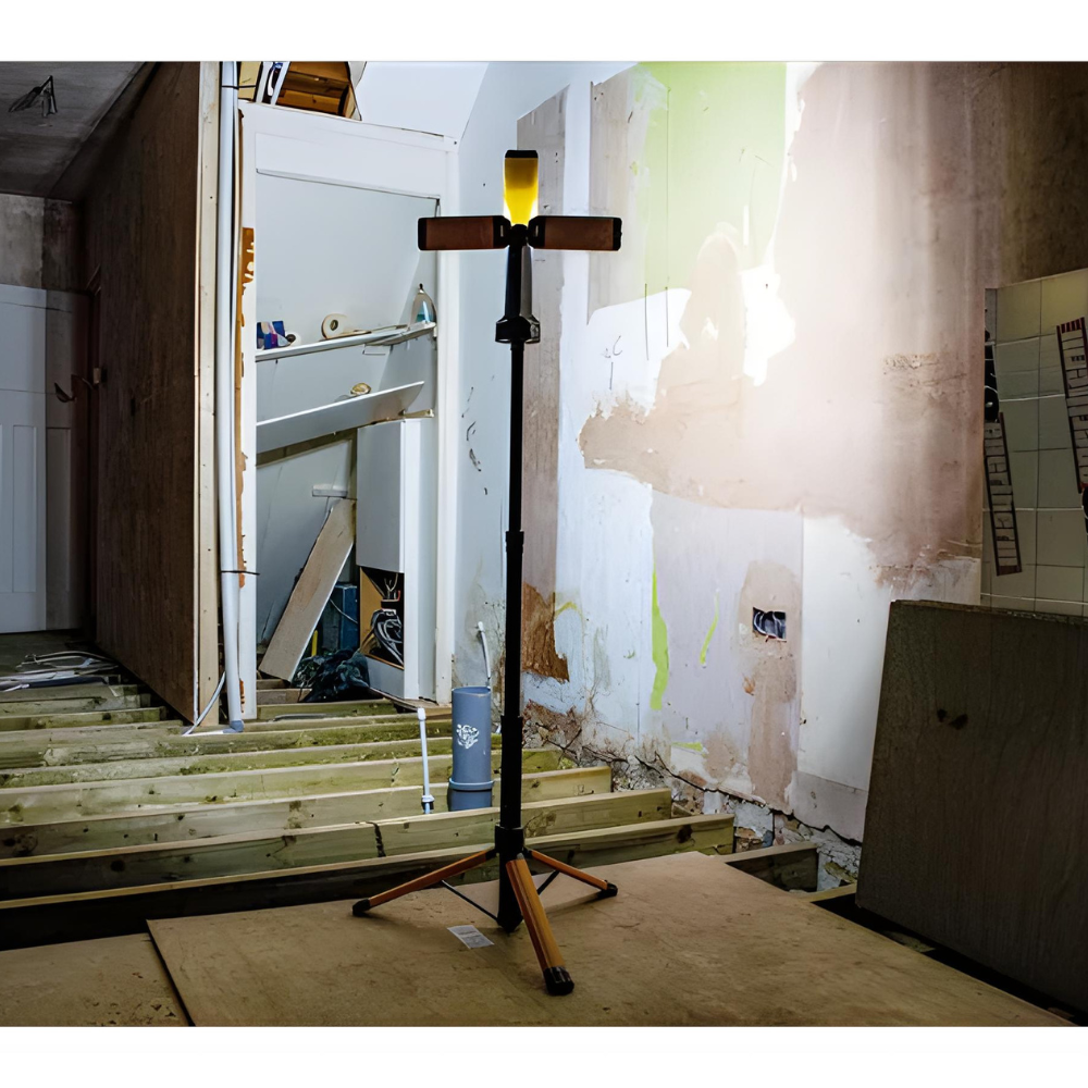 Lamp on a stand in a room under renovation with exposed walls and wooden floor.